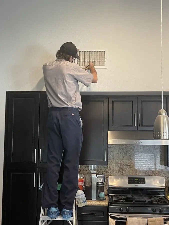 Technician inspecting an air vent during HVAC service in Spring Ridge
